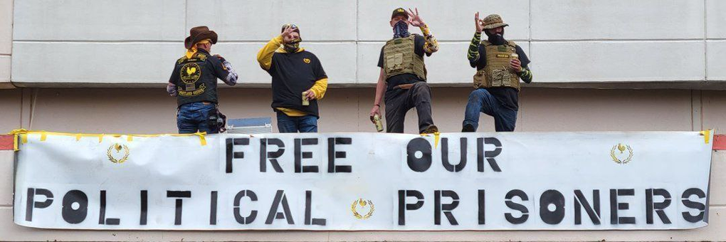 In 2023, four Proud Boys displayed a banner on an abandoned Portland shopping center calling for the release of January 6 insurrectionists (Source: Telegram)