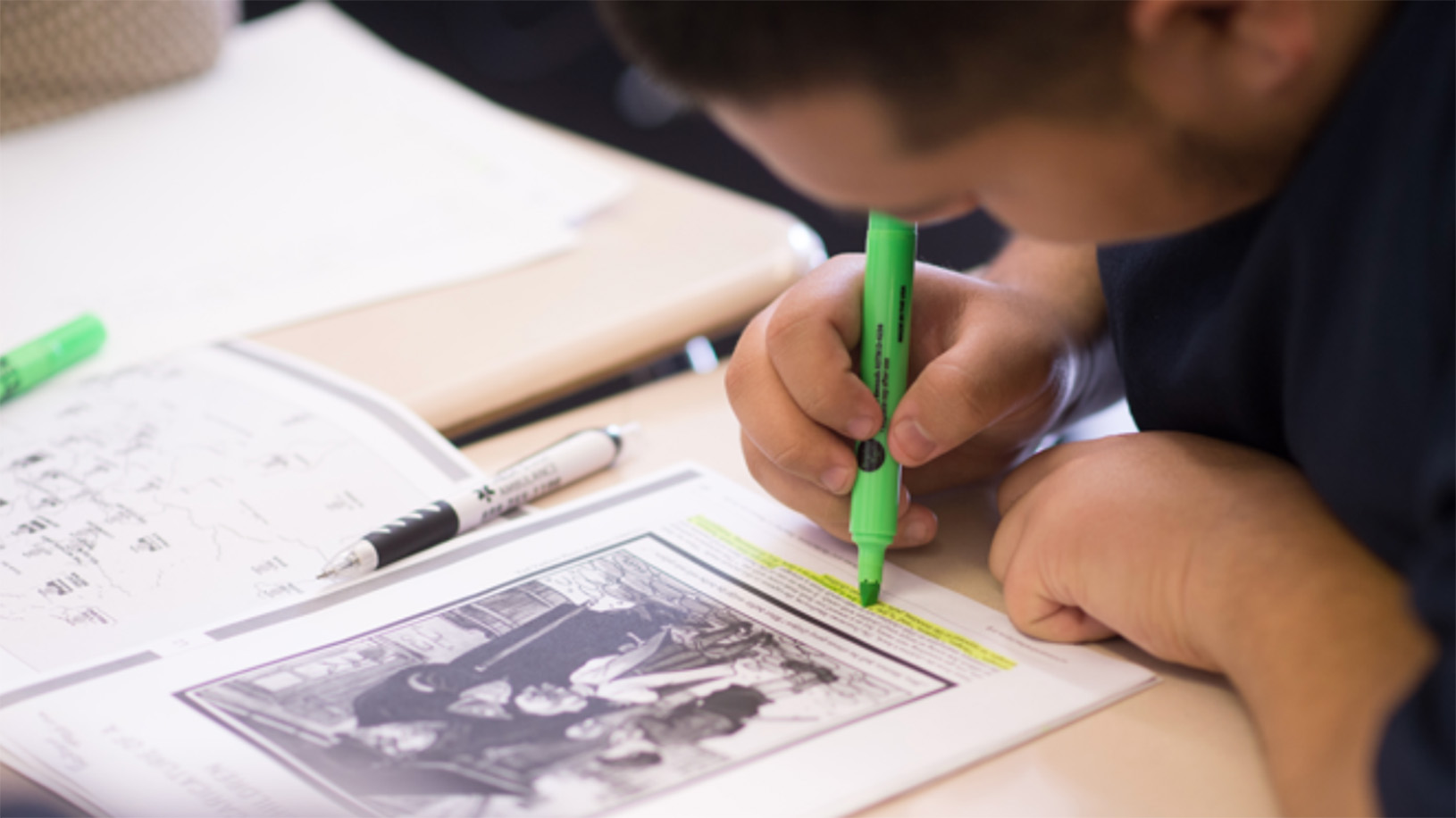 Student working at school desk with paper and highlighter
