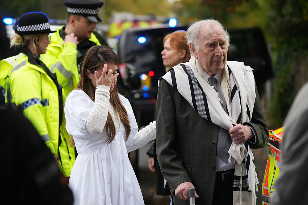 Photo: Congregants are seen as police and other emergency services respond to a car-ramming and stabbing attack that killed two people and injured others at the Heaton Park Hebrew Congregation Synagogue in Manchester, UK, on Yom Kippur, October 2, 2025. (Christopher Furlong/Getty Images)