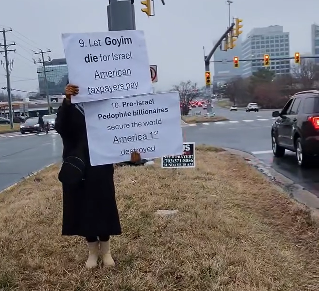 Screenshot: A protester holds a sign with antisemitic language reading, “Let Goyim die for Israel; American taxpayers pay” and “Pro-Israel Pedophile billionaires secure the world America 1st destroyed,” on March 4, 2026, in Tysons, Virginia. (Screenshot/Instagram)