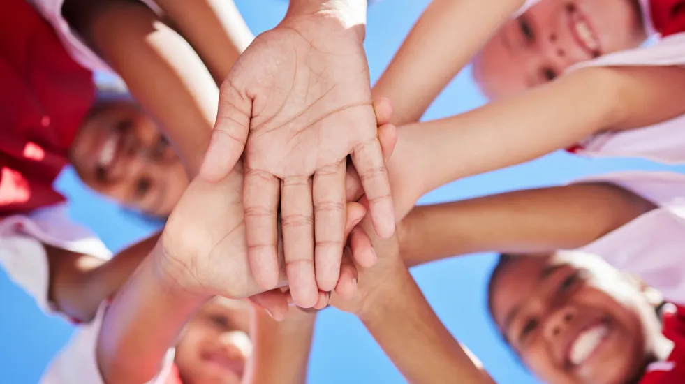 Elementary sports huddle with hands shot from below