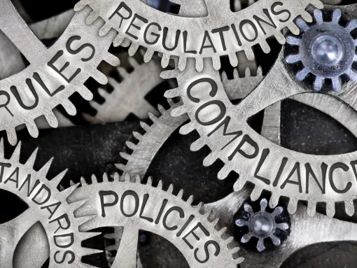 Metal wheels interlocking with words written on them such as rules, policies