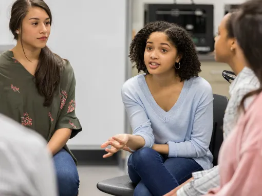 Teenage girl talks during group discussion of a diverse group of teens and adults