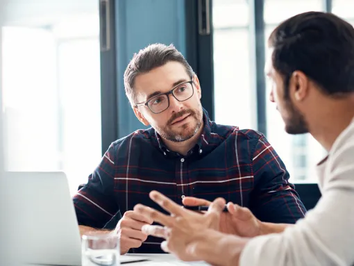 Two people in front of a laptop facing each other exchanging ideas.