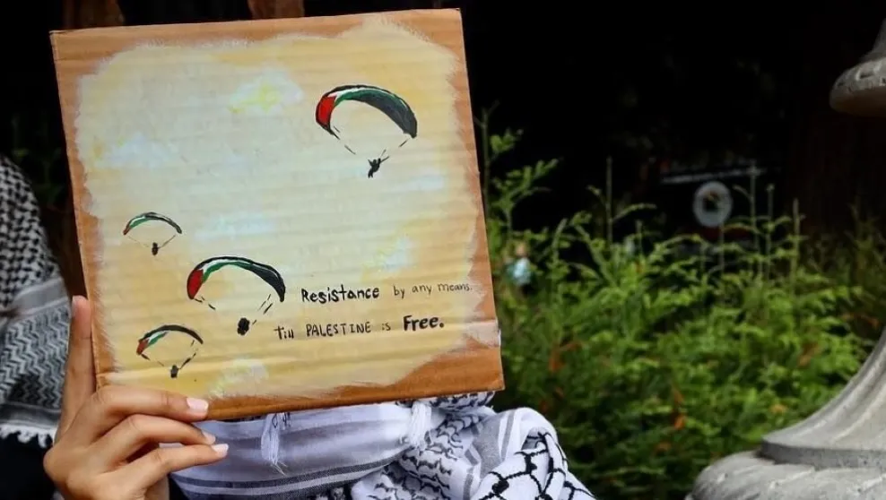 Photo: Berkeley, Cal. -- At an October rally, a protester held a sign with images of paragliders, in reference to Hamas's terrorist attack on October 7. The sign also reads "Resistance by any means Till Palestine is Free."