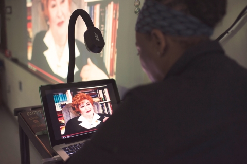 African American teacher looking at holocaust testimony on laptop