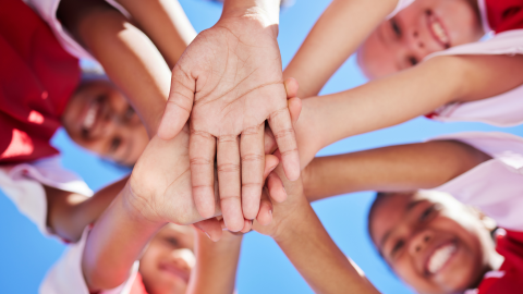 Elementary sports huddle with hands shot from below