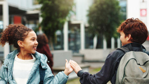 Kids walking by each other outside and giving each other a high five